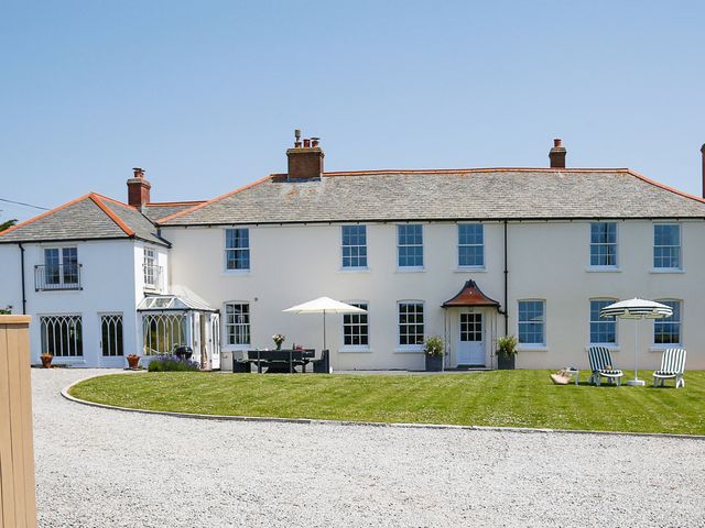 A house with patio chairs and umbrellas at Porthcothan House in St Merryn