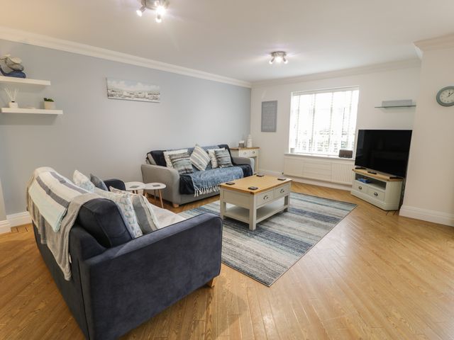 A living room with two sofas a coffee table a television and a window at Apartment 6 in Morfa Nefyn