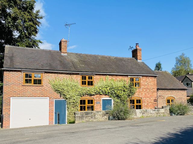 A house with a garage and plants at Yoxall Cottage in Stoke-on-Trent