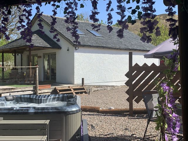A house with a hot tub and a gravel area at Grant Cottage in Strontian