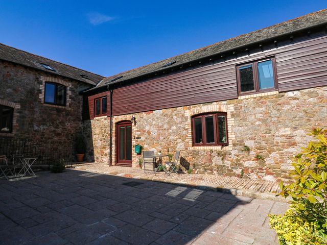 An outdoor area with stone walls and chairs at 3 Town Farm Court in Newton Abbot