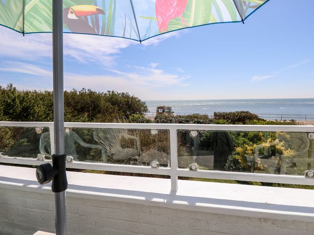 A balcony view with an umbrella overlooking the sea at Bella vista in Selsey, West Sussex
