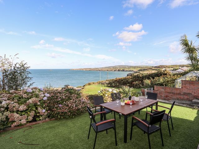 An outdoor patio with a table and six chairs overlooking the sea at Ser a Mor Stars and Sea in Bull Bay near Amlwch
