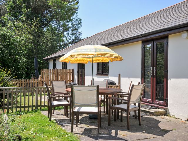 An outdoor patio area with a table and chairs at Columbine Cottage in Bude