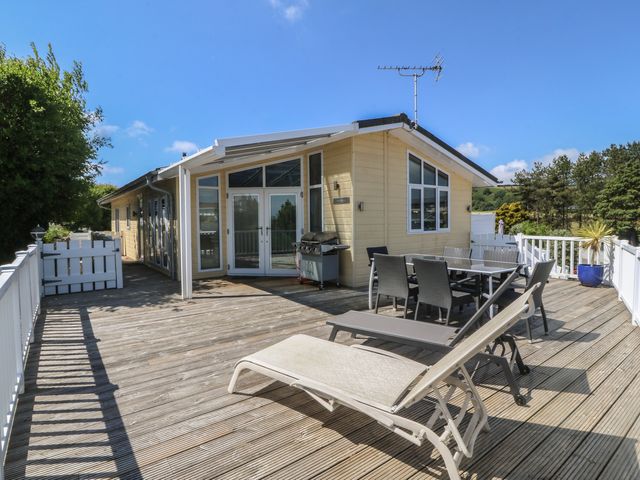 An outdoor patio with dining furniture and a grill at The Warren D26 in Abersoch