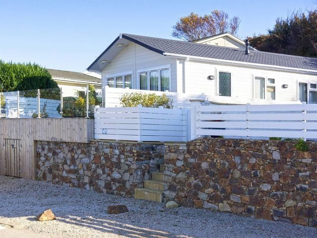 A house with a stone wall and fence at The Warren D7 in Abersoch