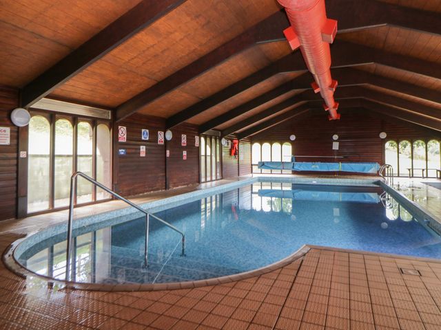 An indoor swimming pool with blue tiled floor and wooden walls at Harcombe House Bungalow 5 Chudleigh