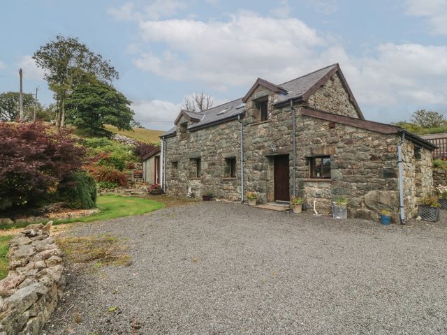 A stone house with gravel driveway and flower pots at Beudy Penarddwnion in Rhydymain near Dolgellau