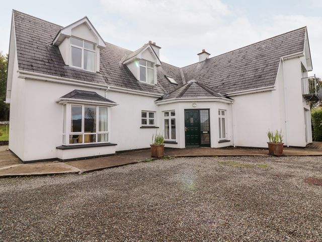 A white two-story house with a gravel driveway and green front door at Seascape Lodge in Kenmare County Kerry