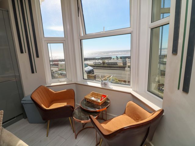 A sitting room with chairs and a table overlooking the ocean at Apt 4 @ Hunter's Quay in Bridlington