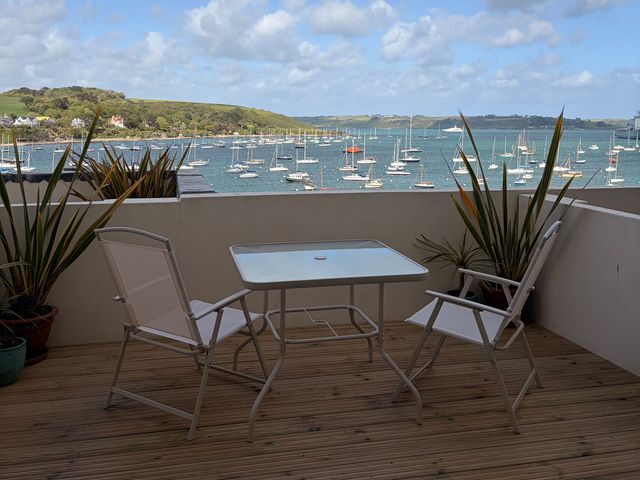 A balcony with a table and chairs overlooking the sea at 58 High Street in Falmouth
