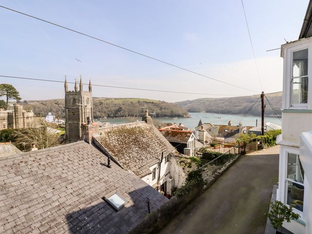 A view of rooftops a church tower a river and hills in the background at Driftwood in Fowey