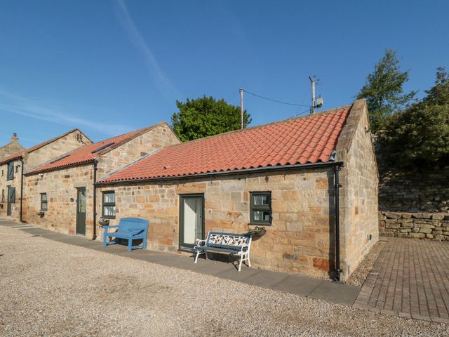 Exterior view of stone buildings with red tiled roofs and benches outside at Valley View in Staithes