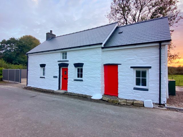 A house with a red door and windows at Pensarngerrig Rhydlewis