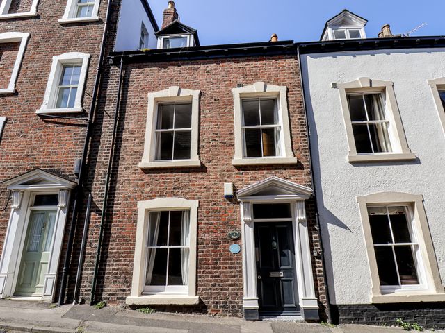A facade of three houses with brick wall and windows at Charlotte House in Whitby