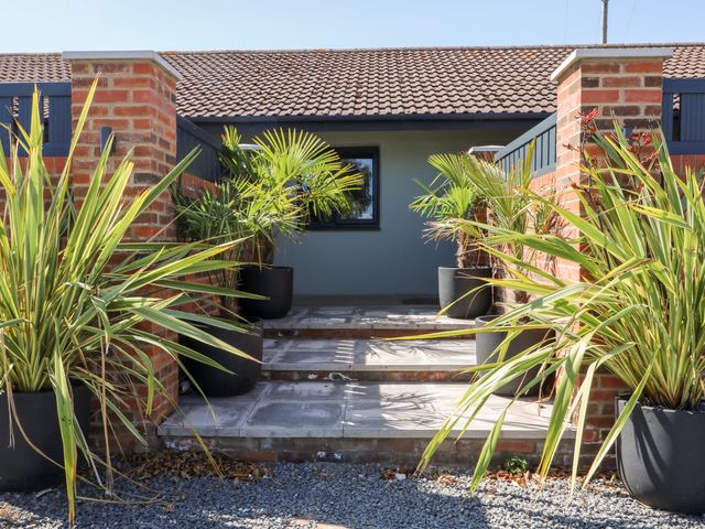 An outdoor entrance area with steps and potted plants between brick pillars at Chalet 1 in Sherburn