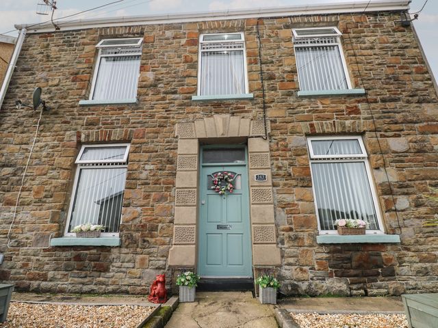 A stone house with a green front door and flower boxes at Brynawel in Burry Port