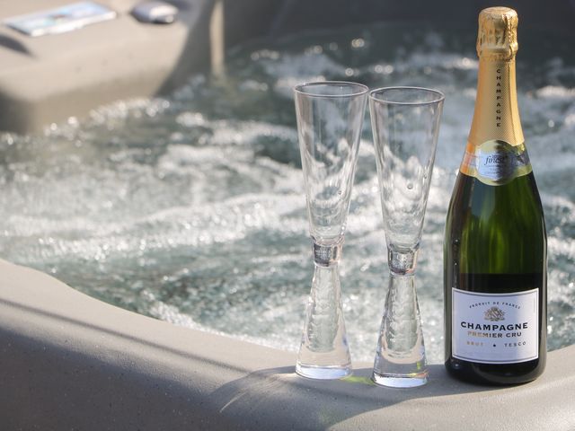 Two empty champagne flutes and a bottle of champagne on the edge of a bubbling hot tub at Chalet 4 East Heslerton near Sherburn
