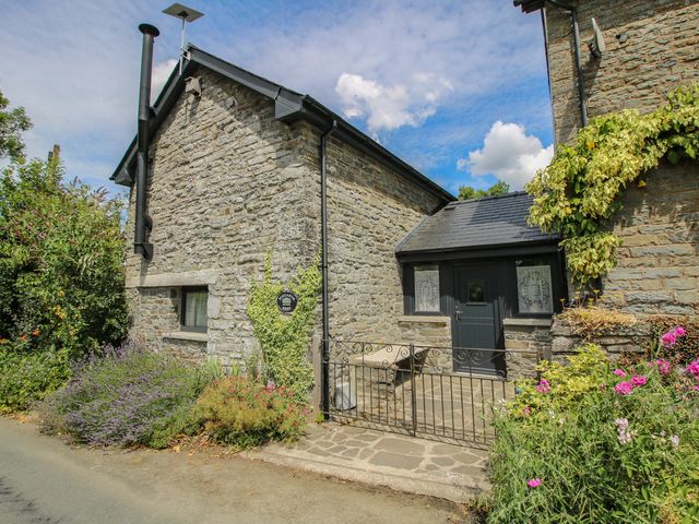 An outdoor view of a stone building with flowers and a pathway at Buzzards Breg in Builth Wells
