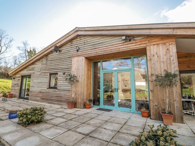 A wooden house exterior with patios and potted plants at Springfield Farm in Moreleigh near Halwell
