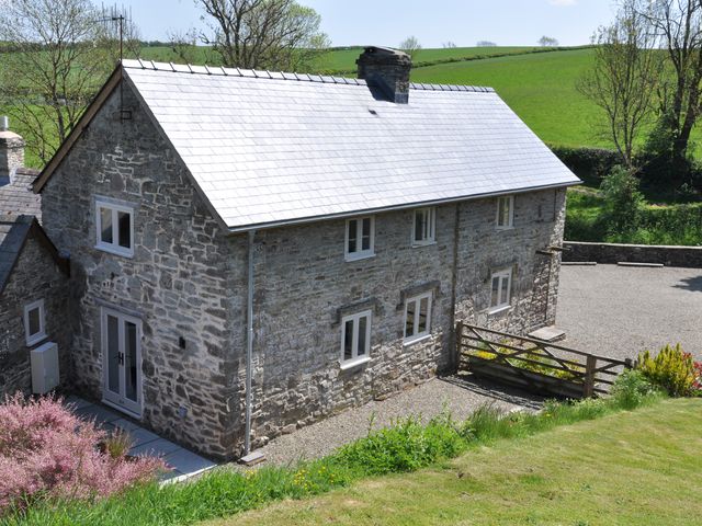 A stone house with a gravel driveway at Rockhill Farmhouse in Clun