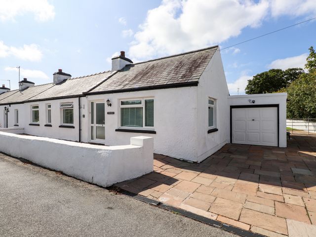 A house with a garage and patio area at 3 Tai Newydd Llanfaelog near Rhosneigr