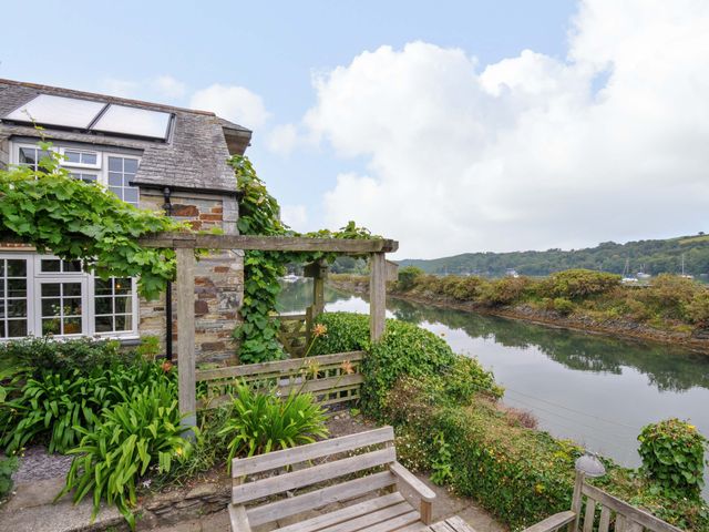 A house beside a river with a wooden bench at Island House in Golant near Tywardreath
