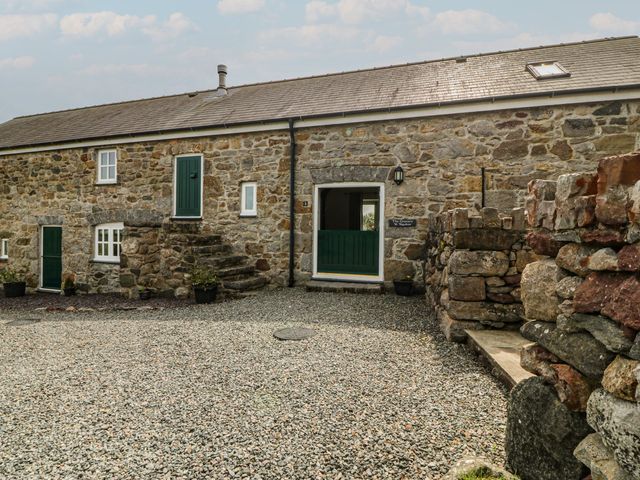 An outdoor area with a stone building and green door at No 1 The Granary Capel Coch near Llannerch-Y-Medd
