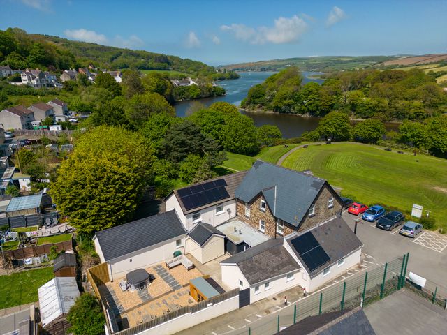 Aerial view of a house with solar panels near a river and green fields at Teifi Villa in St Dogmaels