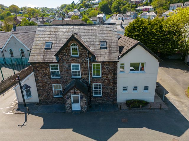 A stone and white building with multiple windows and a small entrance porch surrounded by a paved area at Teifi Villa in St Dogmaels