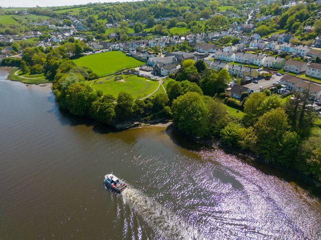 A boat on the water near a green park and residential area at Teifi Villa in St Dogmaels