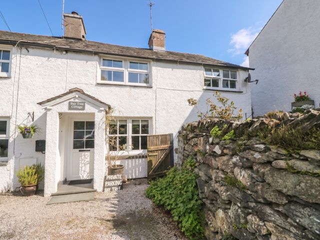 Exterior view of Bay Tree Cottage with a pathway and stone wall in Ambleside