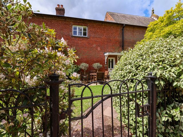 A garden with a wooden table and chairs at Carriage House near Chelford