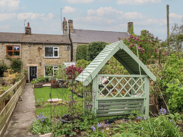 A garden with a greenhouse and flowers at Banklands in Barnard Castle