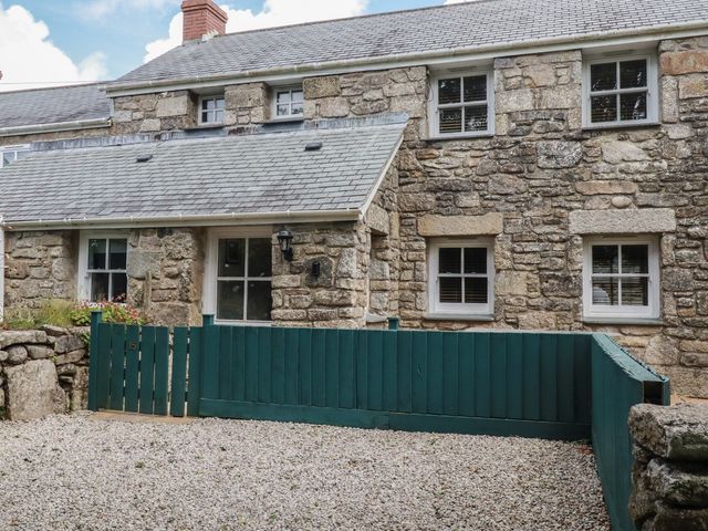 A stone house with windows and a green fence at 15 Boscaswell Downs in Pendeen