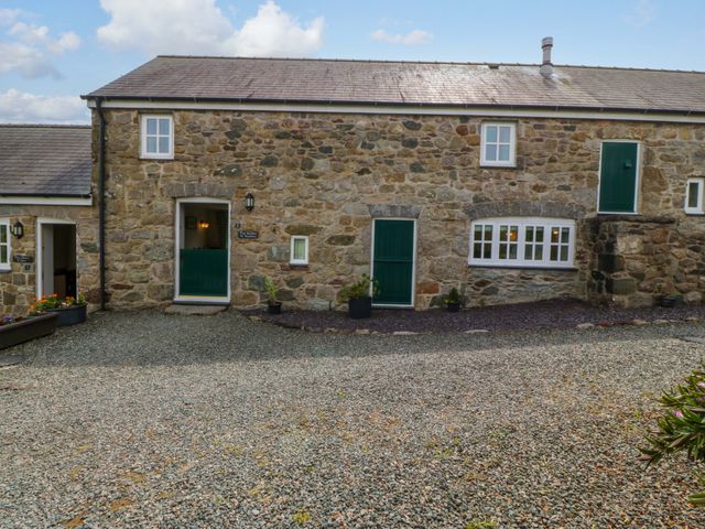 An outdoor view of a stone building with green doors at No 2 The Stables Capel Coch near Llannerch-Y-Medd