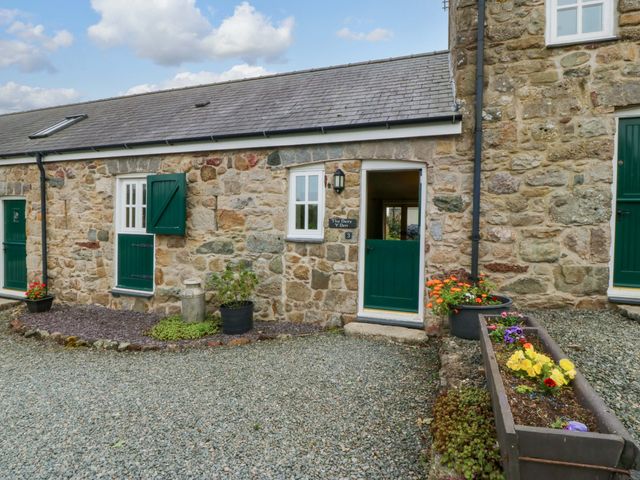 An outdoor view of a stone cottage with green doors at No 3 The Dairy Capel Coch near Llannerch-Y-Medd