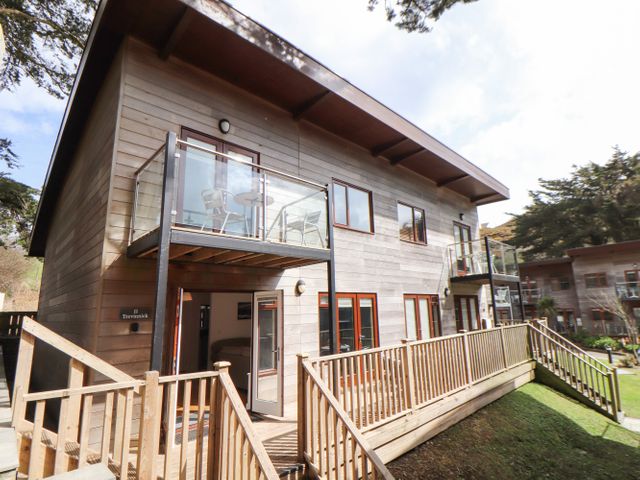 A two-story wooden building with glass balconies and outdoor seating at 11 Towan Valley in Porthtowan