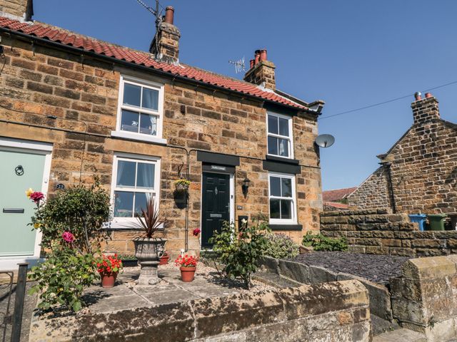 The exterior of a stone cottage with potted plants and flowers outside the front door at Puffin Cottage in Cloughton near Scalby