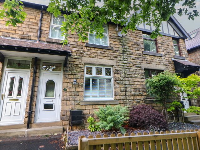 A front view of a house with stone walls and greenery at 16 Oak Bank in Stockport
