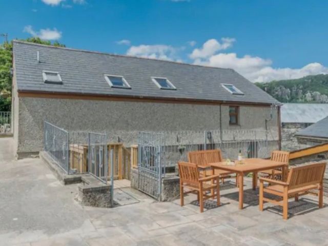 An outdoor dining area with a table and chairs at Llofft Yr Yd in Porthmadog