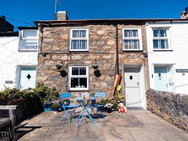 An outdoor patio with blue furniture and plants at Gerallt in Morfa Nefyn