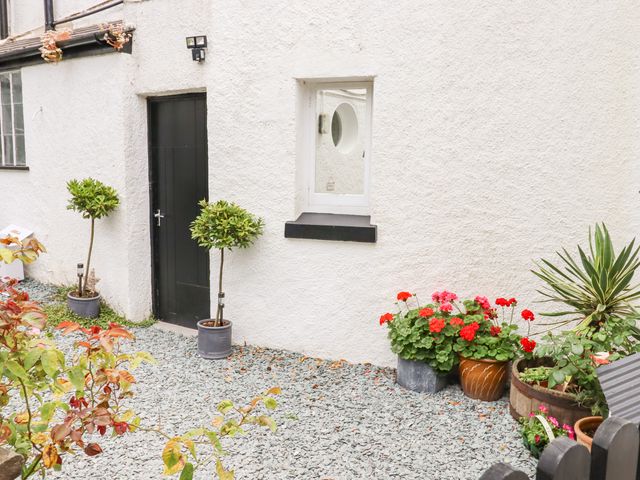 An outdoor area with a black door two potted trees a window and several flower pots at Valley View in Bishopsteignton