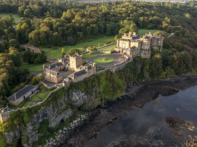 A castle on a cliff surrounded by trees and overlooking a rocky shore at Clocktower - Culzean Castle in Maybole