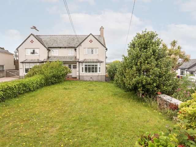 A semi detached house with a front lawn and shrubs at Hillcroft in Abersoch