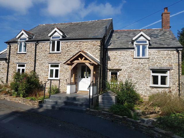 A stone house with a front door and garden at Middle Dean Farmhouse in Trentishoe near Parracombe