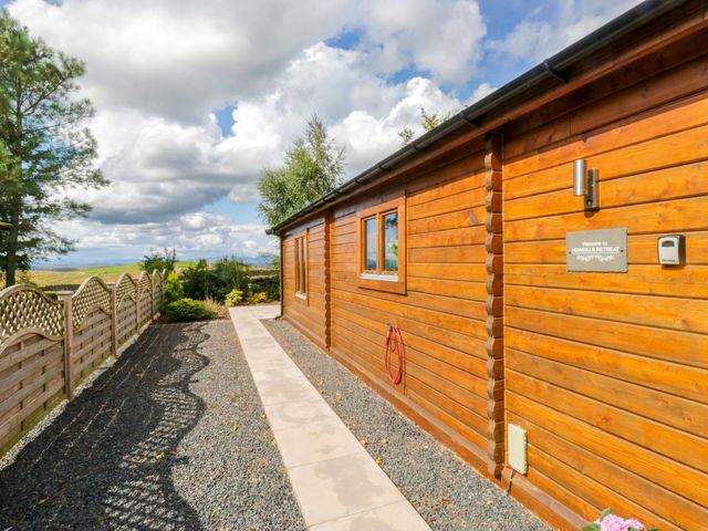 An outdoor area with a log cabin, pathway, and fence at Howgills Retreat at Gatebeck near Kirkby Lonsdale