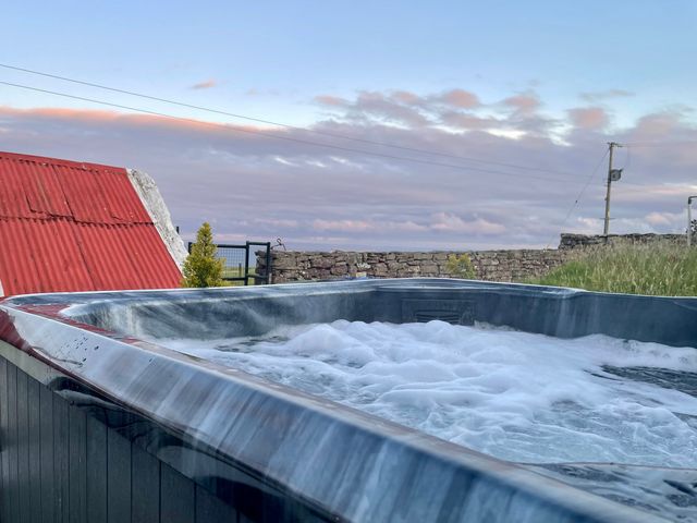 A hot tub with water bubbles near a stone wall at Ceol-na-Mara Newport near Dunbeath