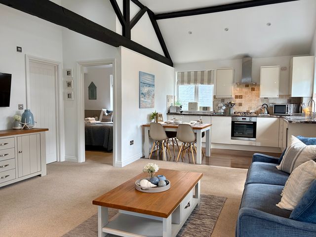 A living room with a sofa and dining area at 11 The Gables in Lyme Regis