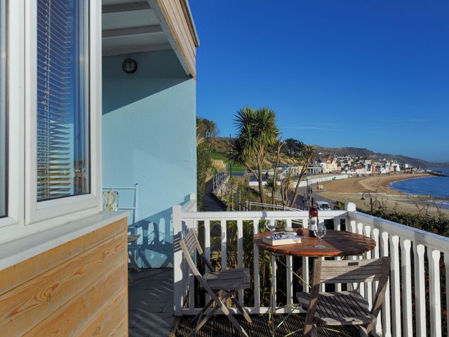 A balcony with a table and chairs overlooking the beach at 1 Wellhayes in Lyme Regis